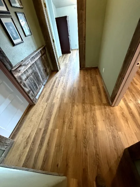 Hallway with newly installed wood-look flooring and a reclaimed wood accent wall