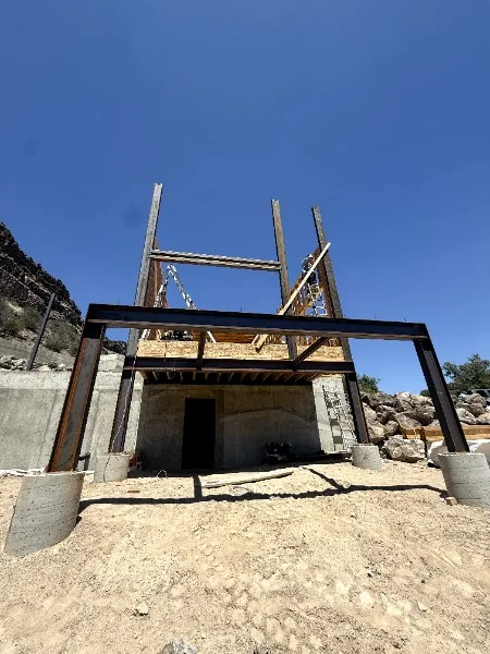 Steel frame rising over a concrete foundation against a blue sky