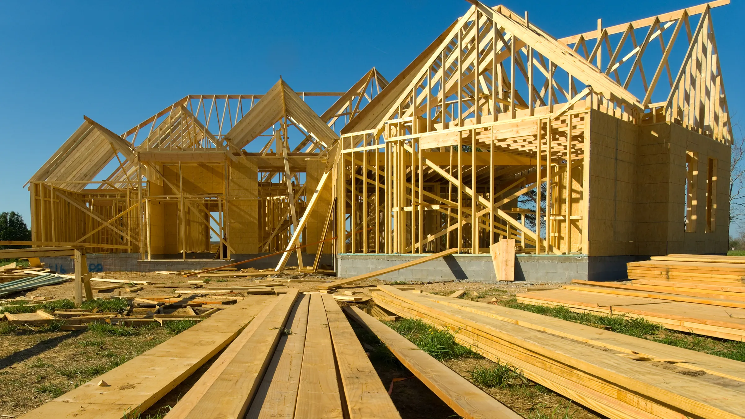New home framing on a building site with lumber laid out in front