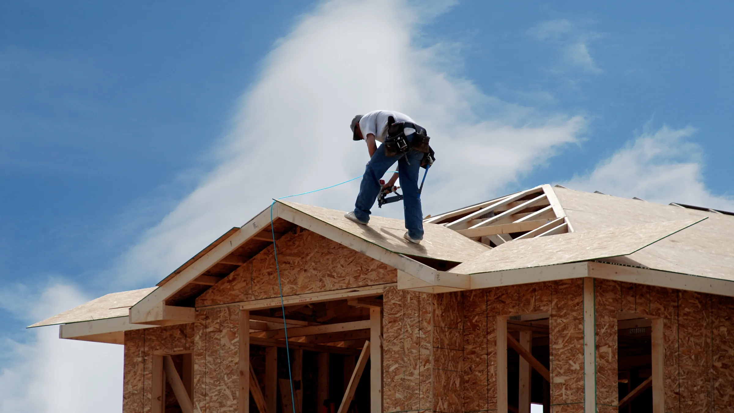 Roofer installing sheathing on a new home under construction