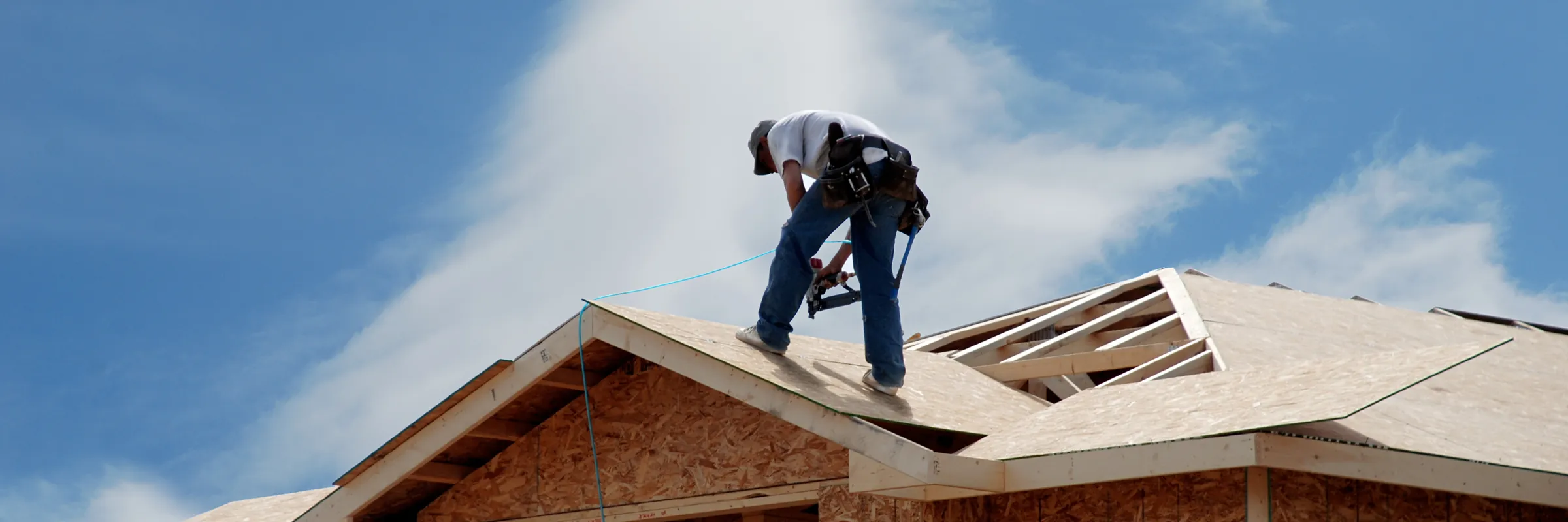 Roofer installing sheathing on a new home under construction